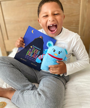 boy missing tooth with blue tooth pillow and adventure book