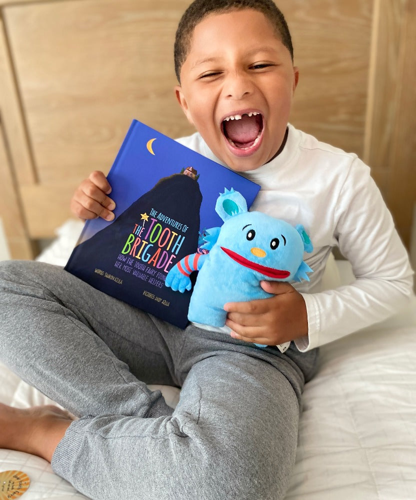 boy missing tooth with blue tooth pillow and adventure book