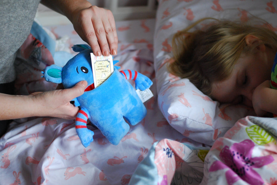 Mom putting money into mouth of tooth pillow monster as girl sleeps